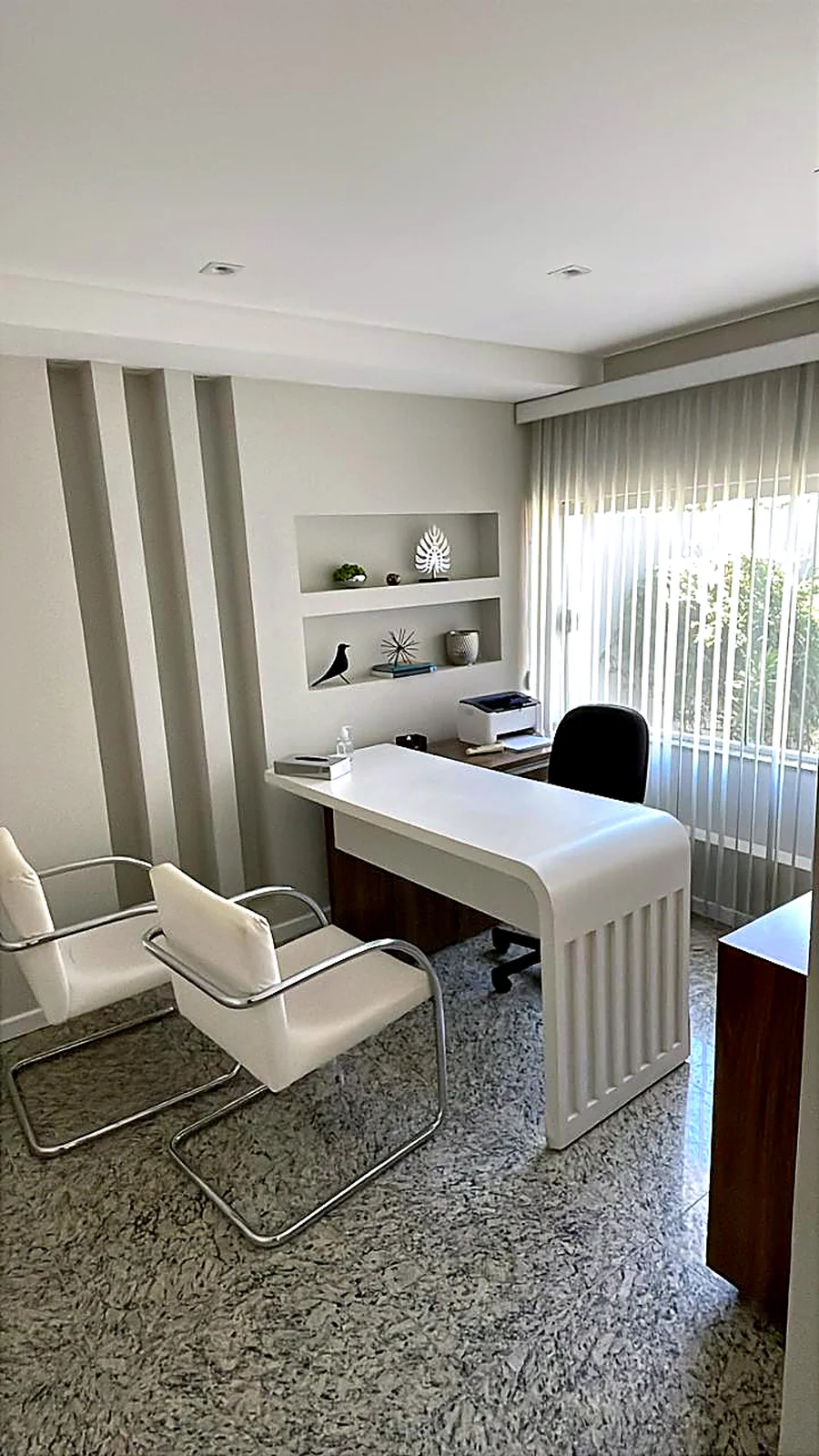 Consultório claro com mesa e poltronas