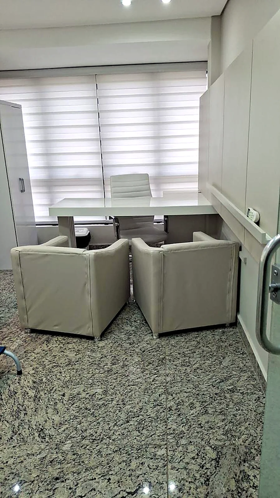 Consultório com mesa e duas poltronas